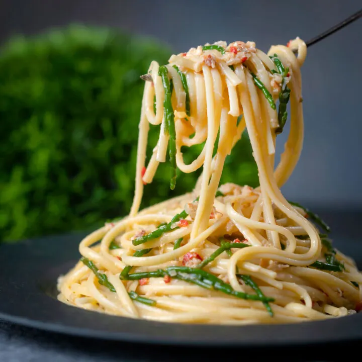 Crab linguine with chilli, lemon and samphire being picked up with a fork.