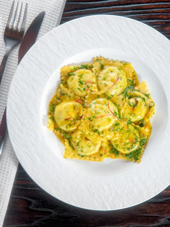 Overhead crab and ricotta ravioli with a saffron and dill butter sauce.