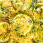 Close-up overhead crab and ricotta ravioli with a saffron and dill butter sauce.