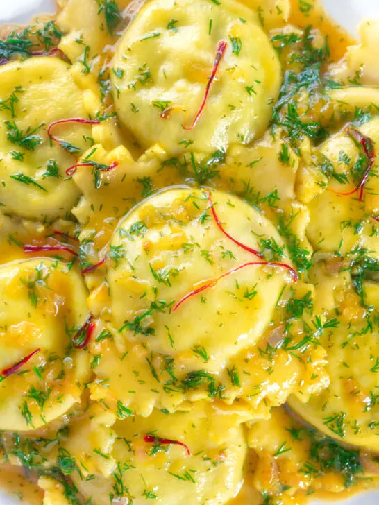 Close-up overhead crab and ricotta ravioli with a saffron and dill butter sauce.