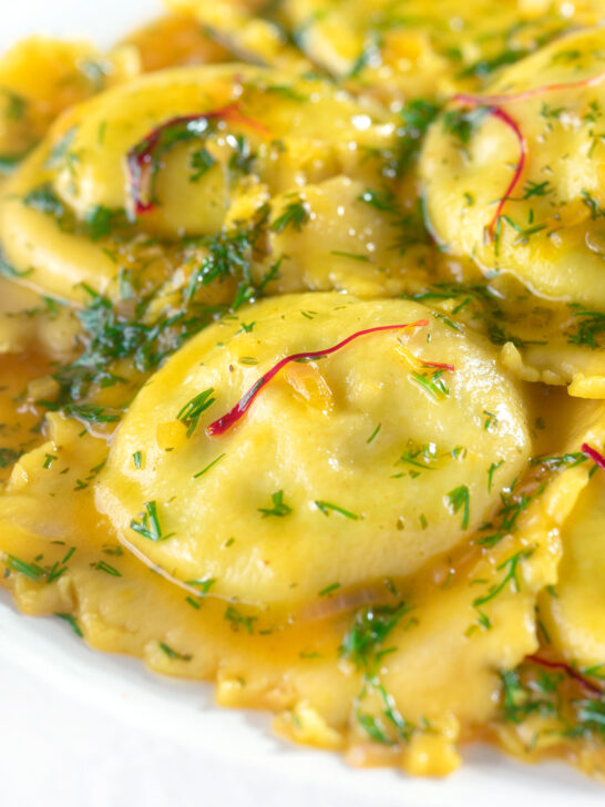 Close-up crab and ricotta ravioli with a saffron and dill butter sauce.