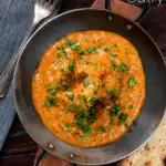 Overhead dum aloo baby potato curry with a tomato gravy featuring a title overlay.