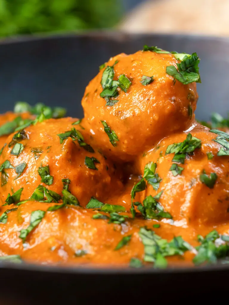 Close-up dum aloo tinned potato curry with a tomato gravy.