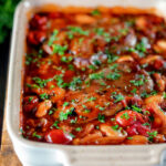 Pork chop casserole with cherry tomatoes and beans in a casserole dish.