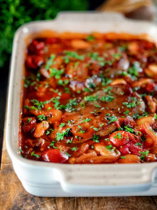 Pork chop casserole with cherry tomatoes and beans in a casserole dish.