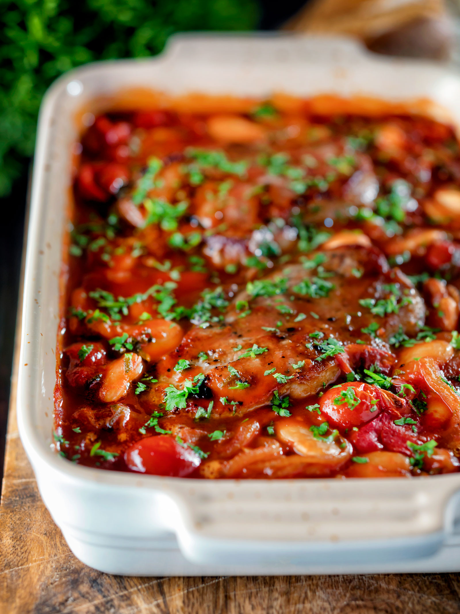 Pork chop casserole with cherry tomatoes and beans in a casserole dish.