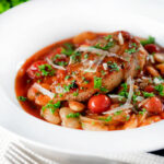 Pork chop casserole with cherry tomatoes and beans served with bread.