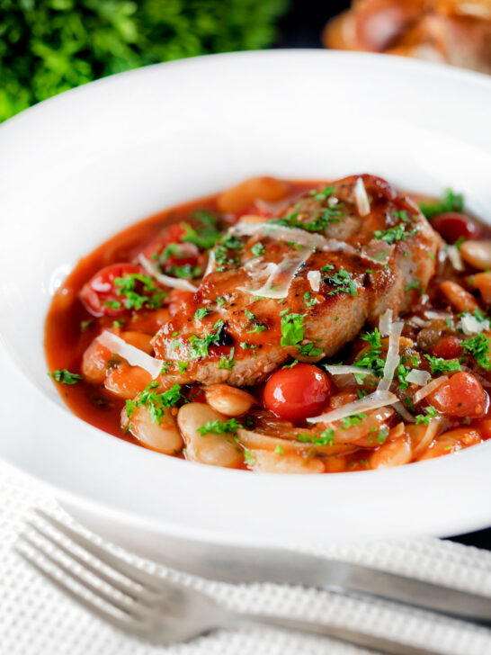 Pork chop casserole with cherry tomatoes and beans served with bread.