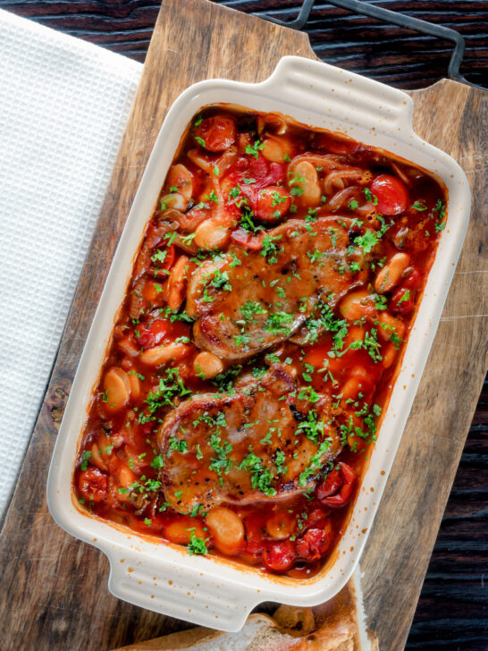 Overhead pork chop casserole with cherry tomatoes and beans in a casserole dish.