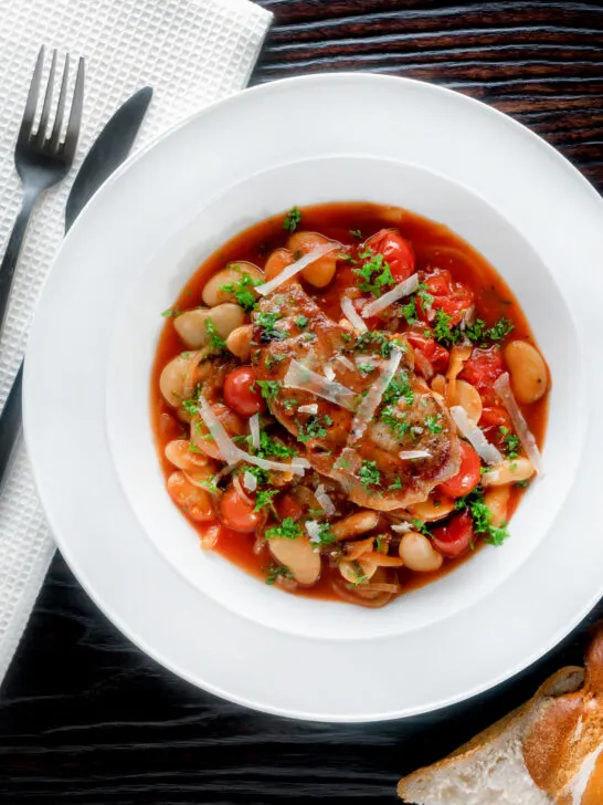 Overhead pork chop casserole with cherry tomatoes and beans served with bread.