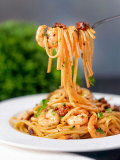 Prawn and chorizo pasta with fresh parsley being picked up with a fork.