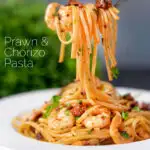 Prawn and chorizo pasta with fresh parsley being picked up with a fork featuring a title overlay.