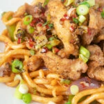 Close-up Chinese salt and pepper chicken served with noodles.