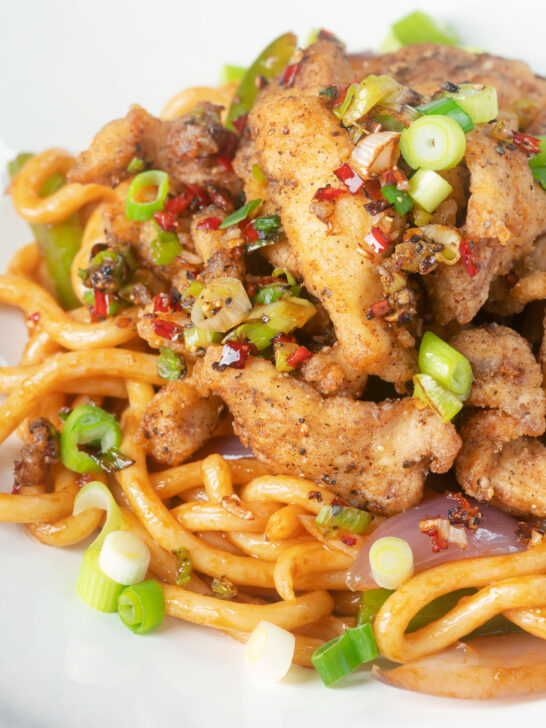 Close-up Chinese salt and pepper chicken served with noodles.