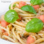 Close-up pasta pesto alla trapanese fresh tomato and basil featuring a title overlay.