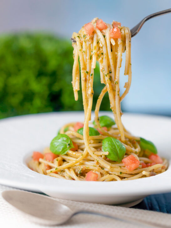 Pasta pesto alla trapanese fresh tomato and basil being picked up with a fork.