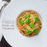 Overhead pasta pesto alla trapanese fresh tomato and basil featuring a title overlay.