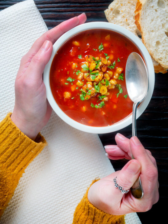 Overhead spicy vegan sweetcorn soup with tomato and chipotle being eaten.