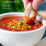 Bread being dipped into a spicy vegan sweetcorn soup featuring a title overlay.