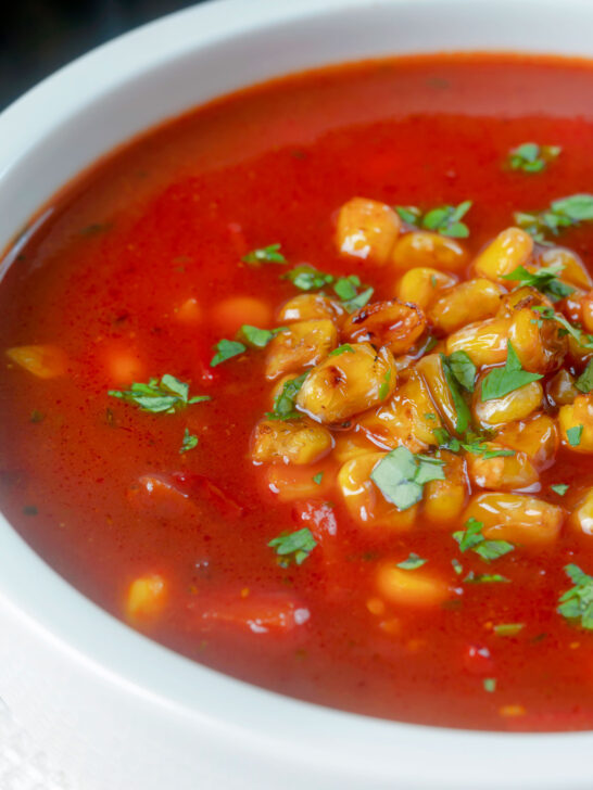 Close-up spicy vegan sweetcorn soup with tomato and chipotle.