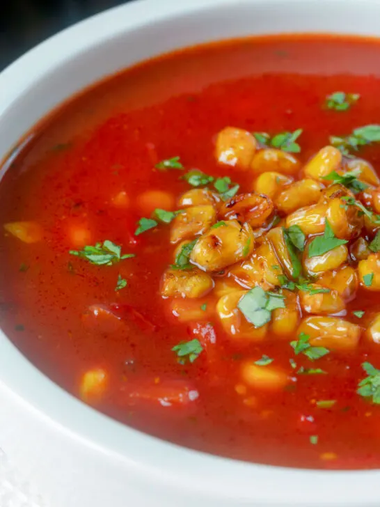 Close-up spicy vegan sweetcorn soup with tomato and chipotle.