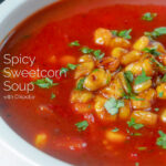 Close-up spicy vegan sweetcorn soup with tomato and chipotle featuring a title overlay.