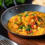 Vegan sweet potato and chickpea curry with coconut milk and fresh coriander featuring a title overlay.