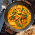 Overhead sweet potato and chickpea curry with coconut milk and fresh coriander featuring a title overlay.