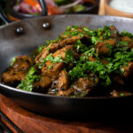 Close-up Tamil black pepper chicken curry, aka Chettinad chicken with kachumber salad.