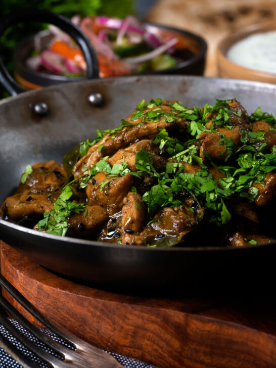 Close-up Tamil black pepper chicken curry, aka Chettinad chicken with kachumber salad.