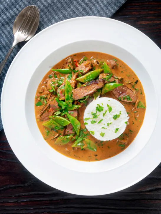 Overhead Thai red beef curry with sugar snap peas and coconut milk sauce.