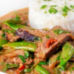 Close-up Thai red beef curry with sugar snap peas and coconut milk sauce.