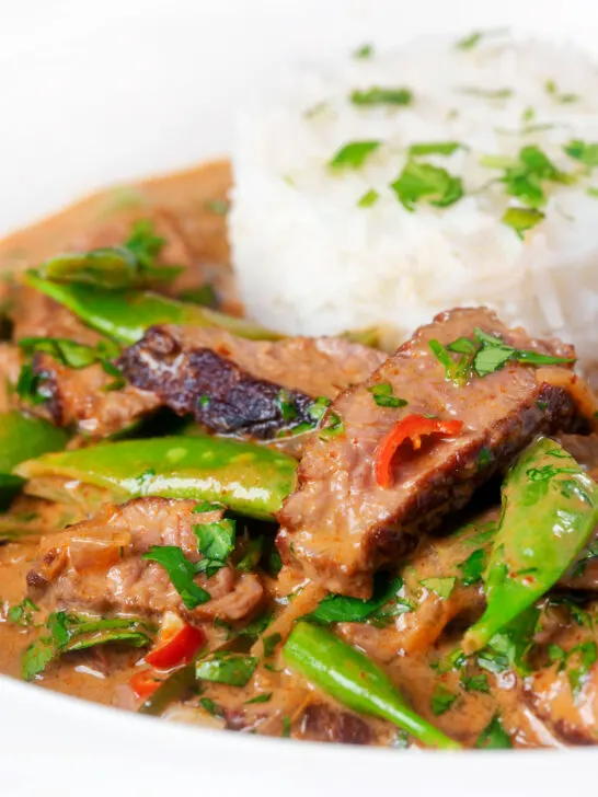 Close-up Thai red beef curry with sugar snap peas and coconut milk sauce.