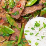 Overhead close-up Thai red beef curry with sugar snap peas and coconut milk sauce.
