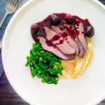 Overhead wild boar haunch steak with blackberry sauce, cabbage and mashed potato.