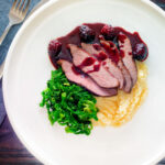 Overhead wild boar haunch steak with blackberry sauce, cabbage and mashed potato featuring a title overlay.