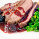 Close-up wild boar haunch steak with blackberry sauce, cabbage and mashed potato.