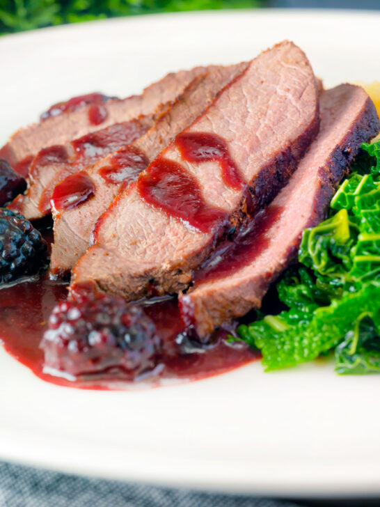 Close-up wild boar haunch steak with blackberry sauce, cabbage and mashed potato.