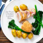 Overhead chicken cordon bleu cooked in an air fryer served with potatoes and broccoli featuring a title overlay.