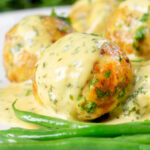 Close-up ground chicken meatballs with honey, mustard sauce and green beans.