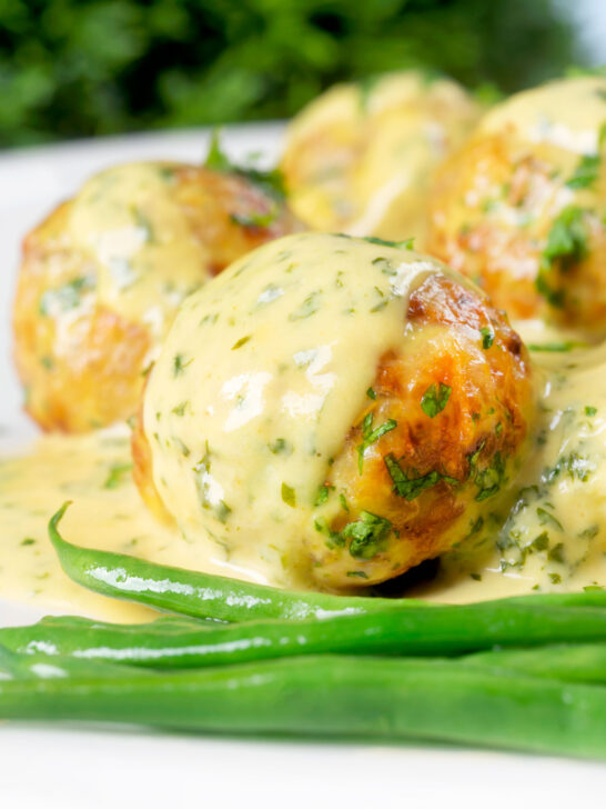 Close-up ground chicken meatballs with honey, mustard sauce and green beans.