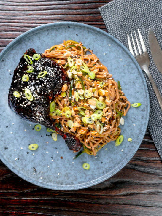 Overhead sticky hoisin duck leg served with a cucumber and soba noodle salad.