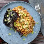 Overhead sticky hoisin duck leg served with a cucumber and soba noodle salad featuring a title overlay.