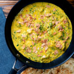 Chicken pasanda yoghurt, coriander and almond curry served in a cooking pan with a naan bread.