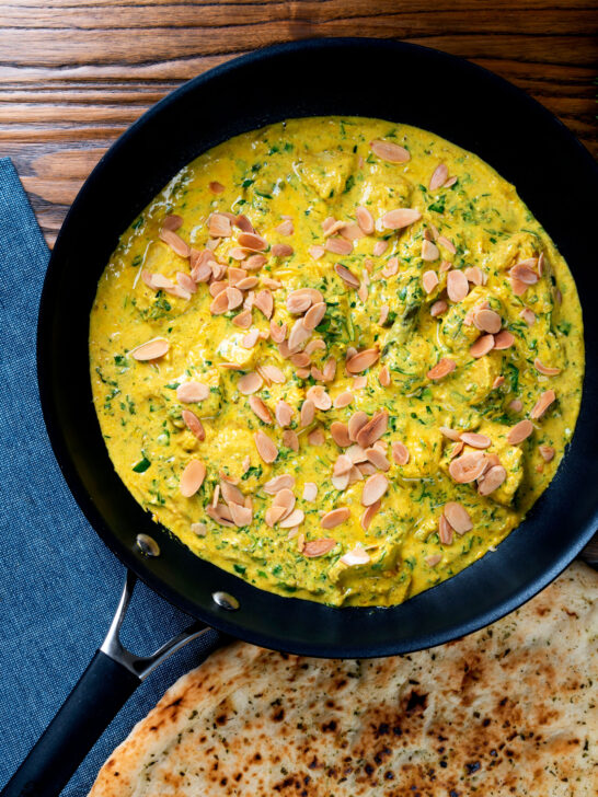 Chicken pasanda yoghurt, coriander and almond curry served in a cooking pan with a naan bread.