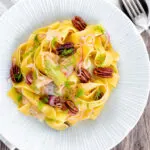 Overhead fennel and orange pasta with red onions and pecan nuts.