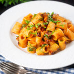 Red pesto halloumi pasta with mezzi rigatoni and fresh basil.