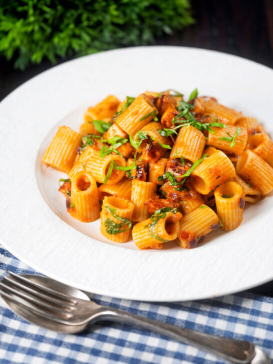 Red pesto halloumi pasta with mezzi rigatoni and fresh basil.