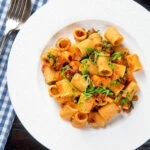 Overhead red pesto halloumi pasta with mezzi rigatoni and fresh basil.
