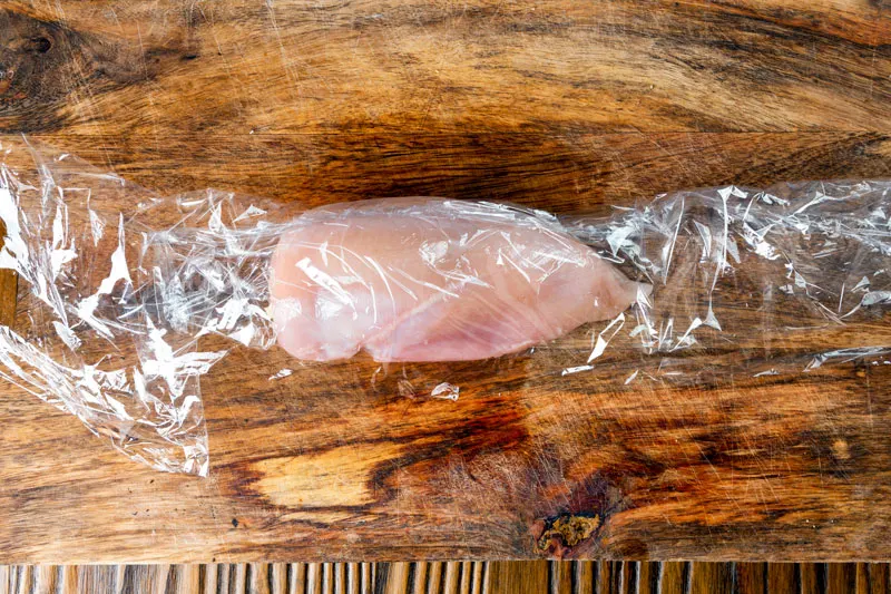 Chicken breast in cling film ready to be rolled.